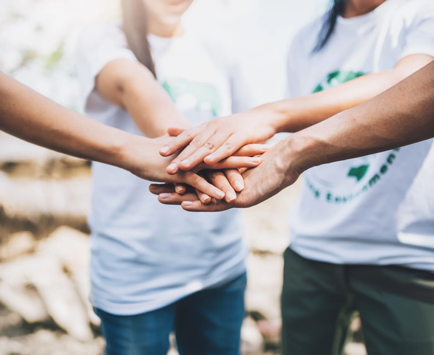 A diverse group joins hands to show unity and teamwork.