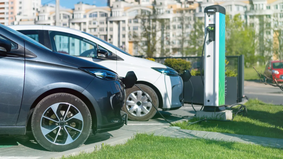 Two electric vehicles connected to a public charging station.