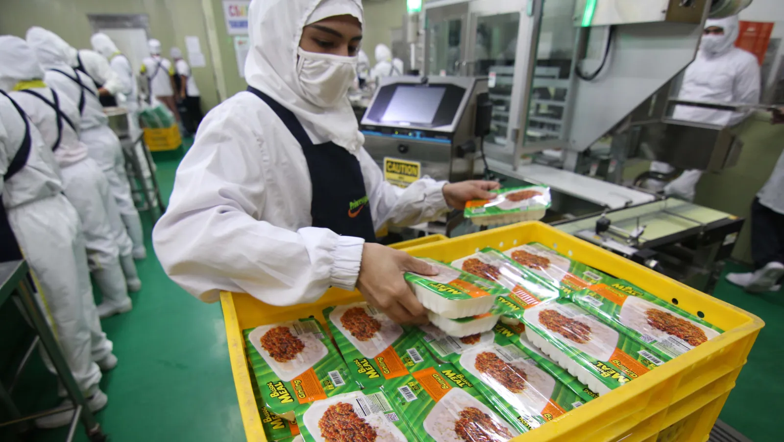Jolliant employee packs food on a production line.