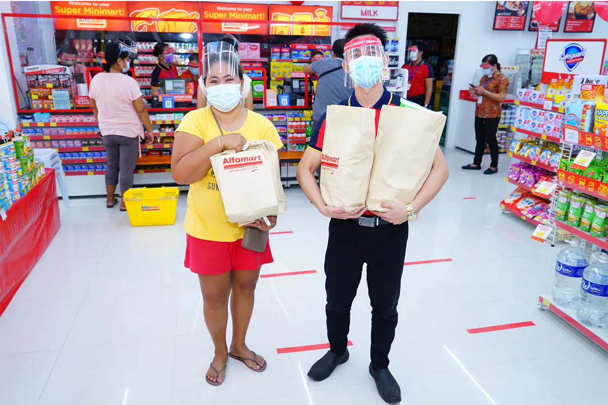 Alfamart representatives display products in a store.