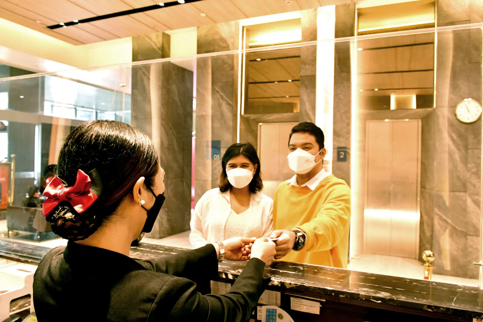 Hotel employees assist a guest at reception.
