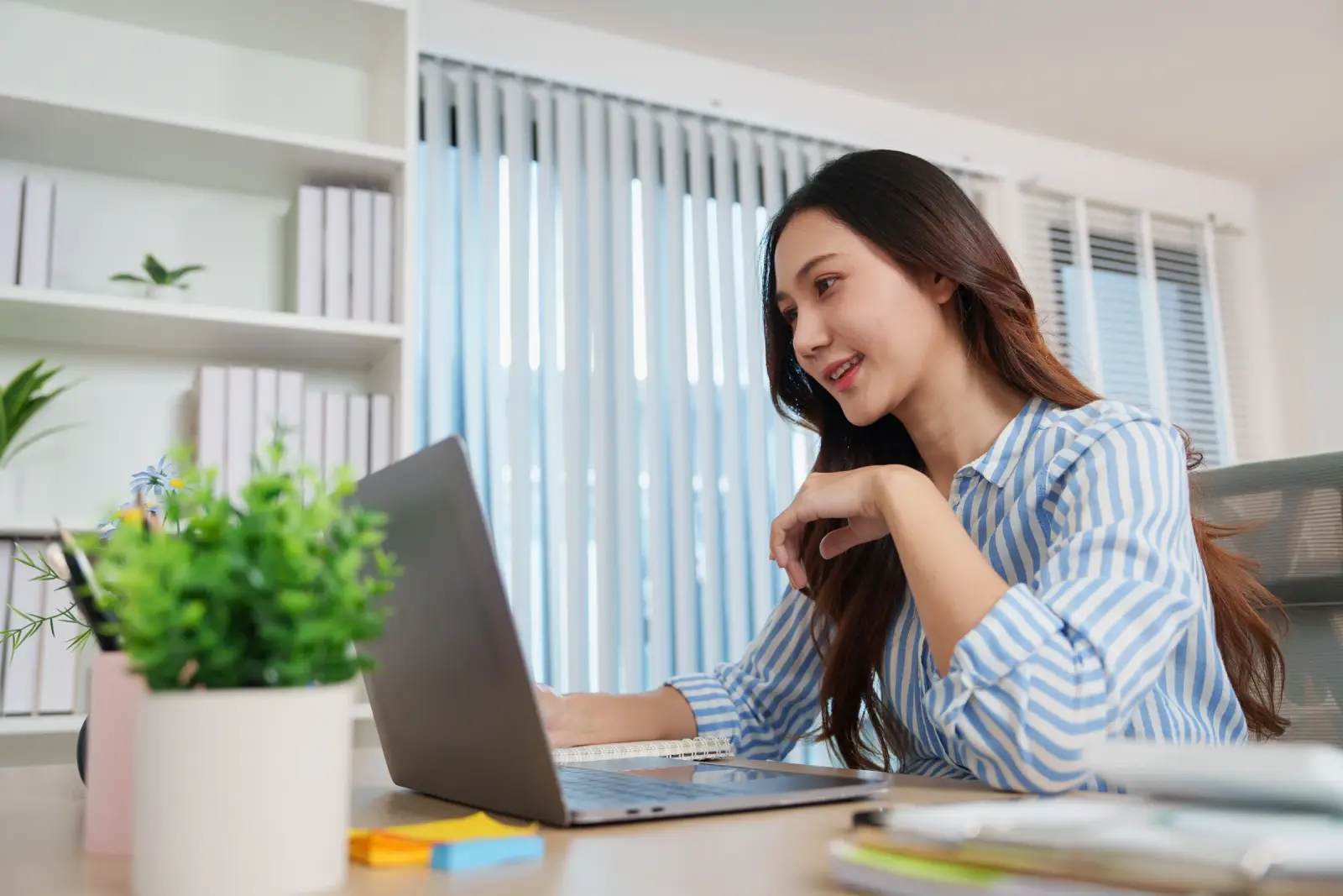 A woman uses a laptop at a desk.