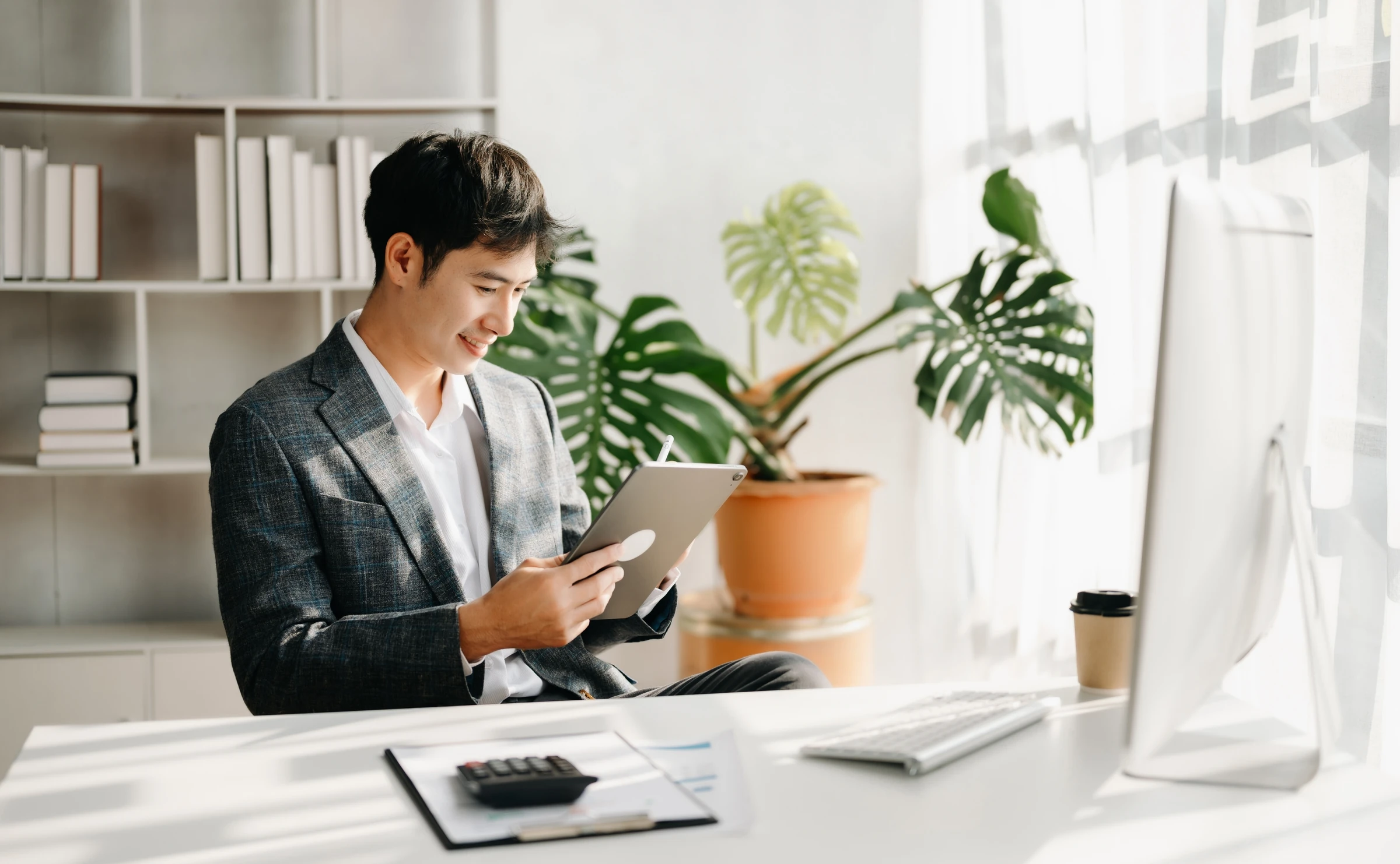 A man uses a tablet at a desk.