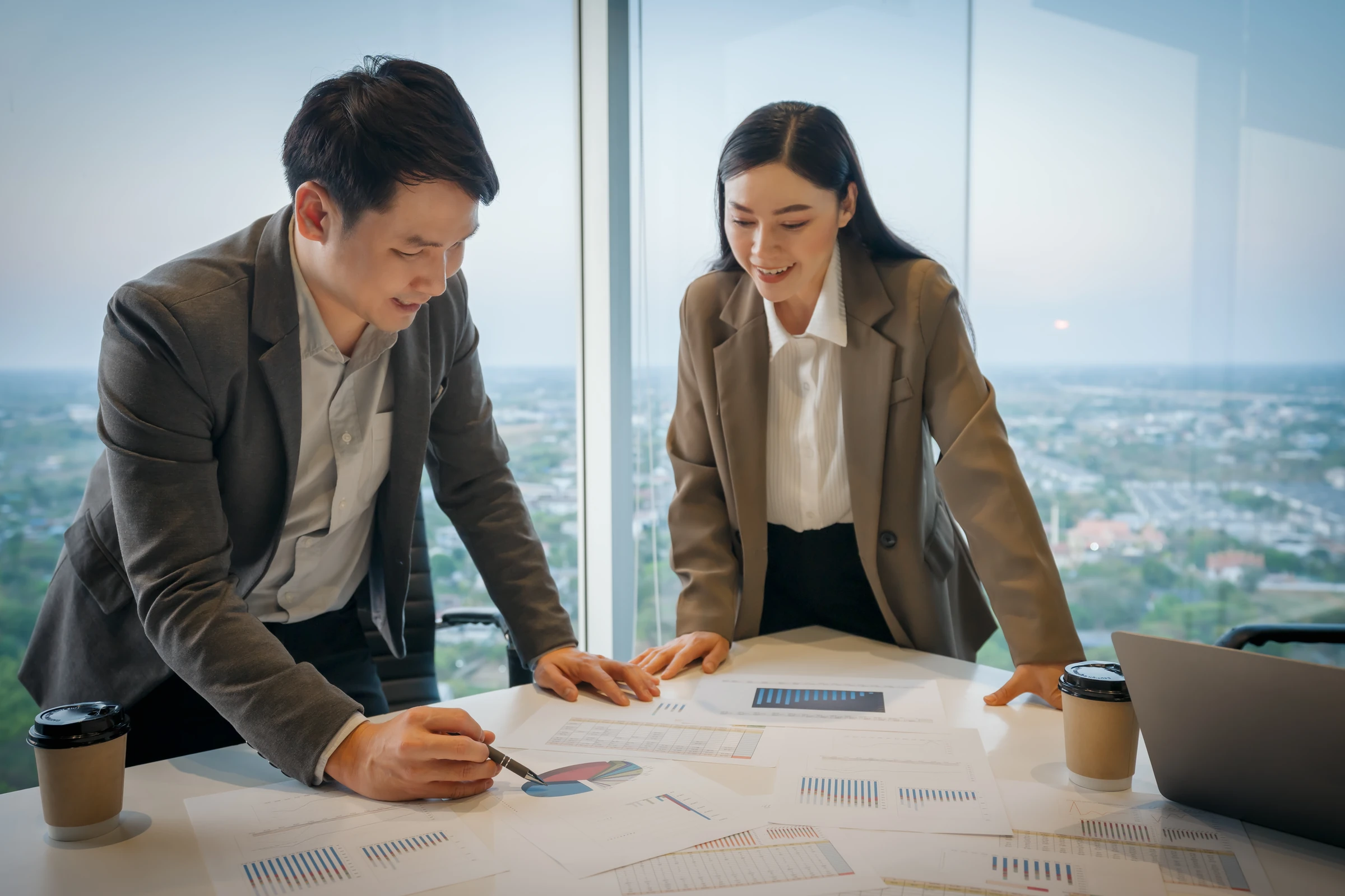 Two colleagues review documents on a meeting table.