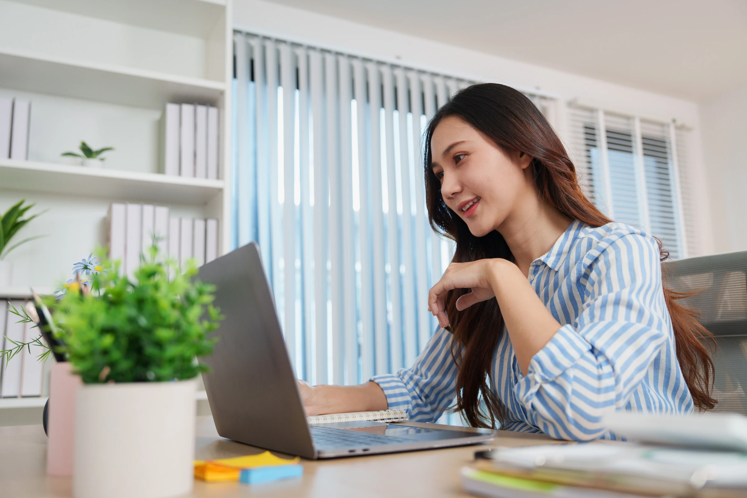 A woman uses a laptop at a desk.