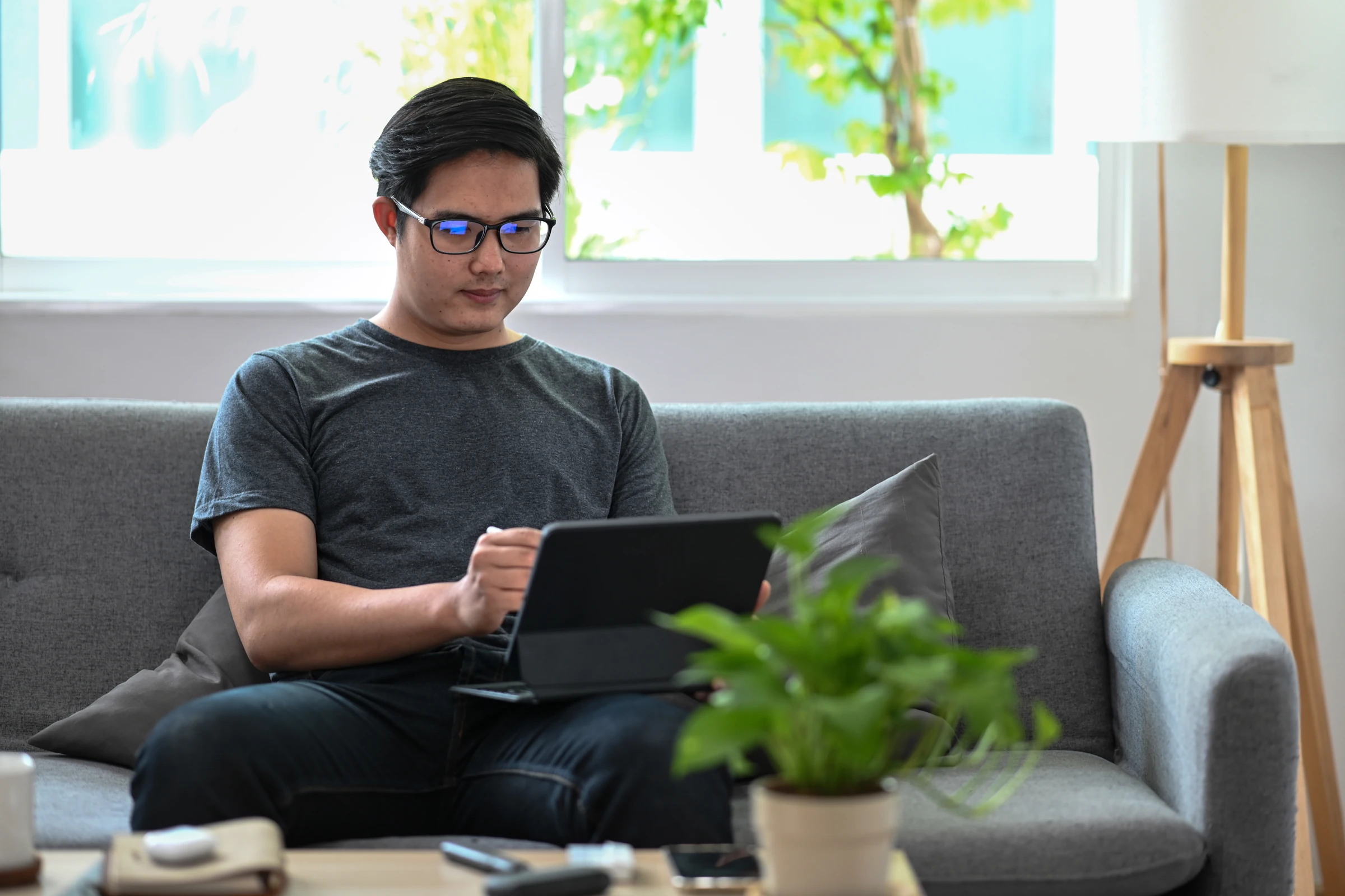 A man uses a tablet while sitting on a sofa.