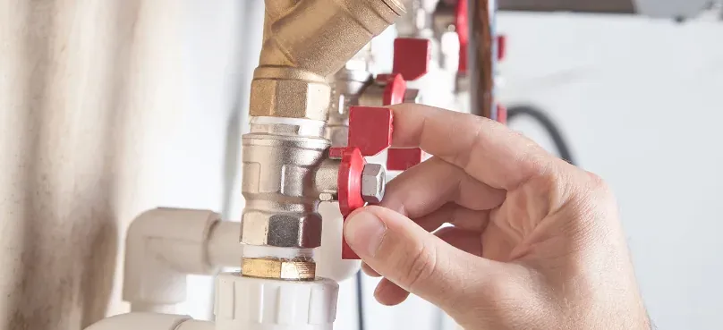 A hand turning the valve of an LPG gas line