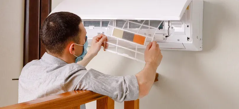 A technician cleaning the filter of a split-type air conditioner