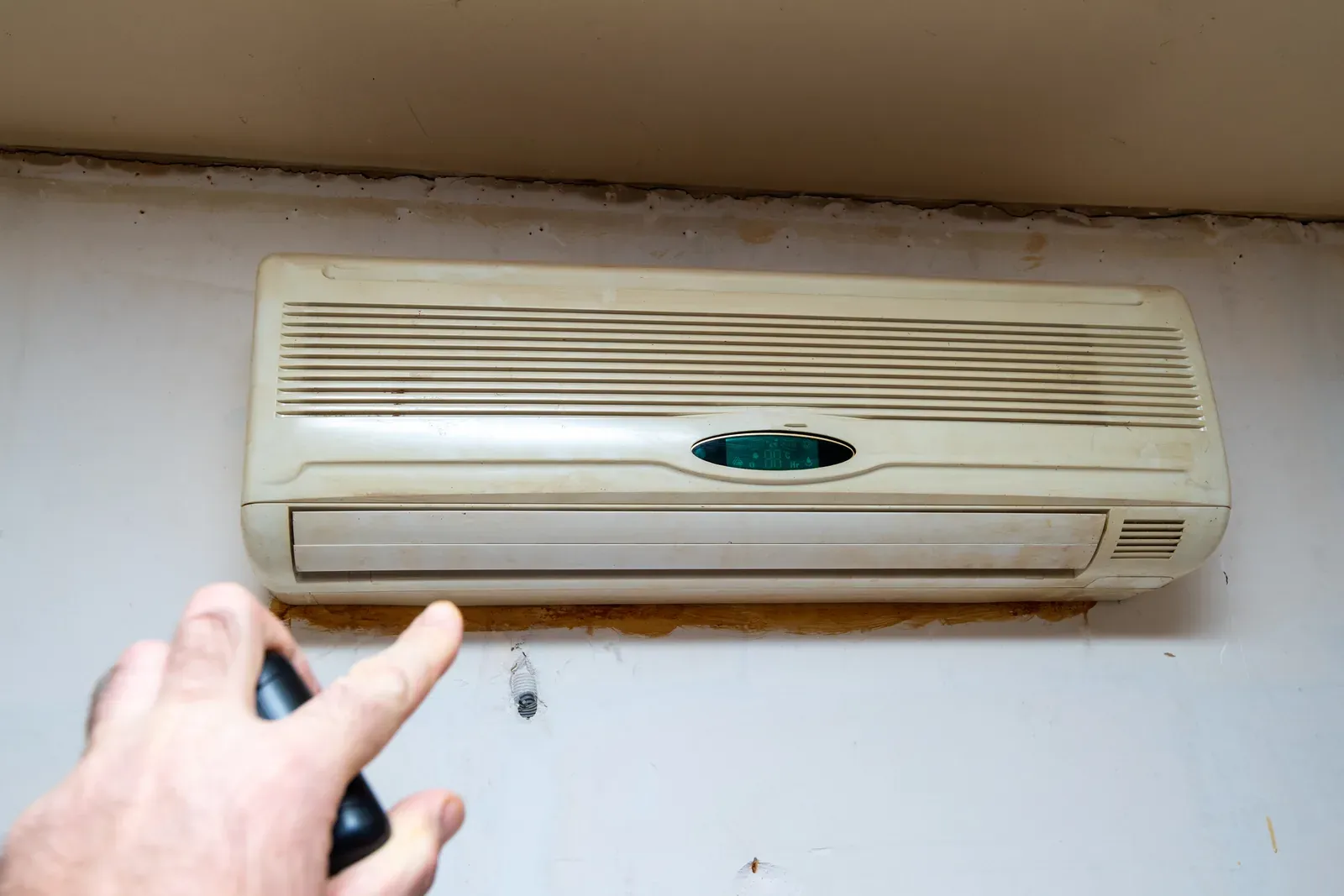 An old window-type air conditioner being operated with a remote control