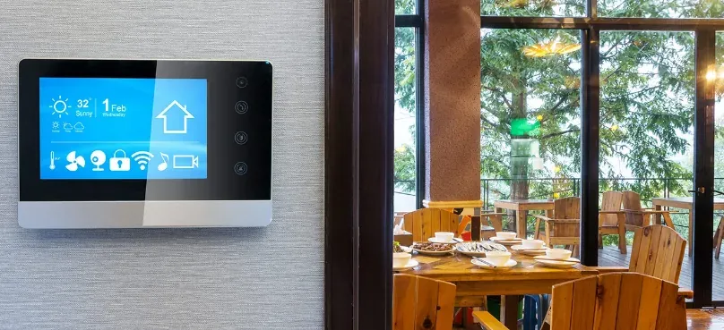 A smart thermostat panel mounted on the wall of a restaurant