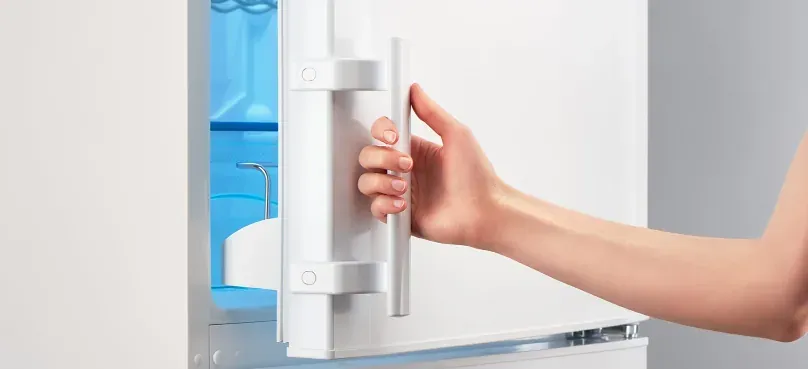 A hand closing a refrigerator door