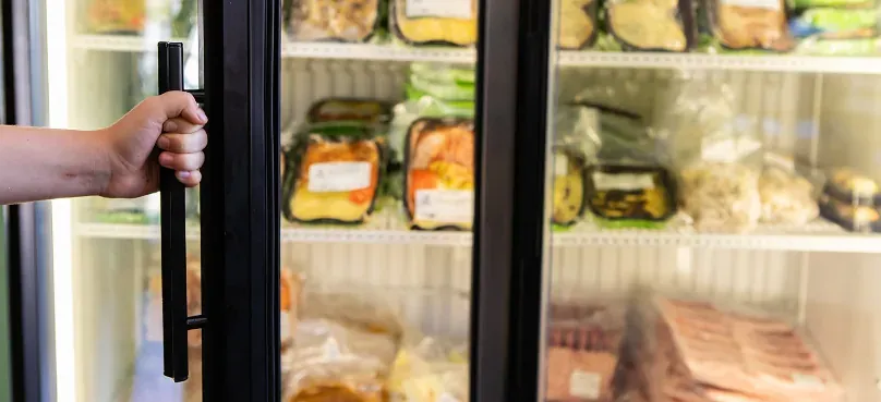A glass-door commercial freezer stocked with frozen goods