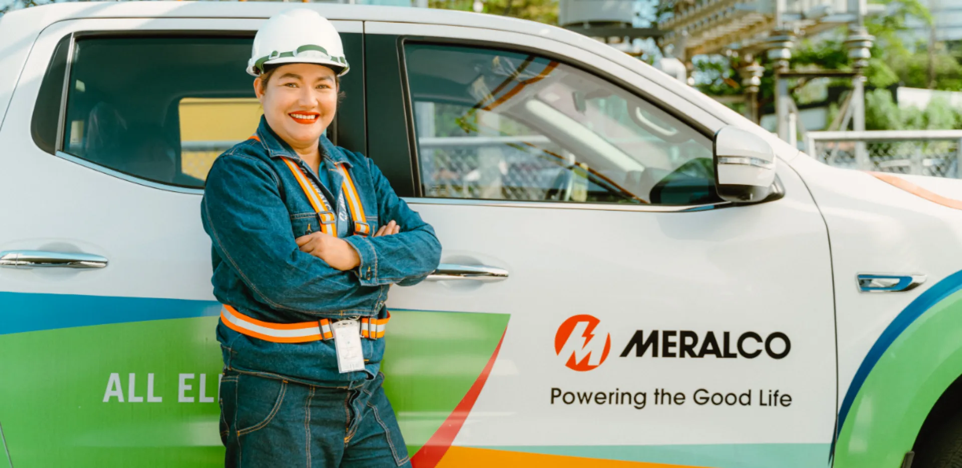 Meralco employee beside an all-electric company vehicle