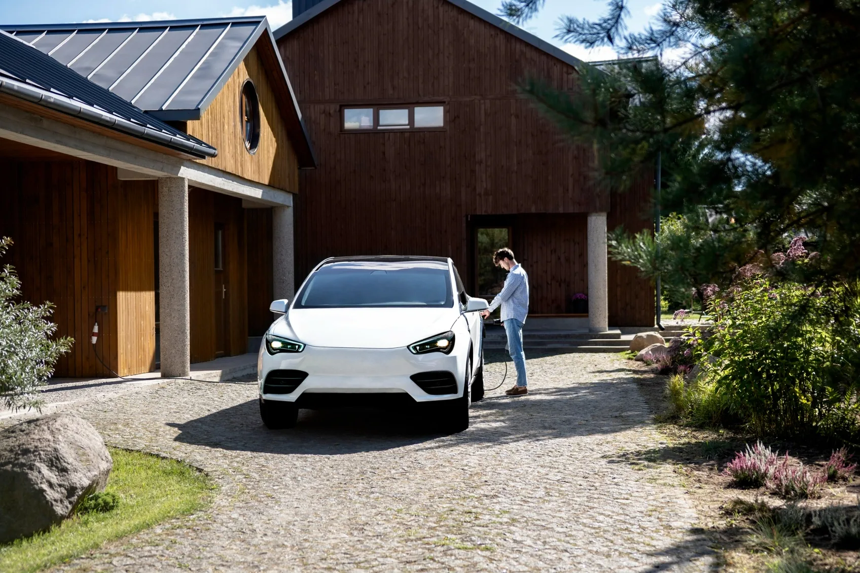 Electric car parked in a home driveway beside a charger