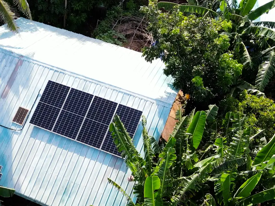 Solar panels installed on the roof of a rural health facility surrounded by trees.