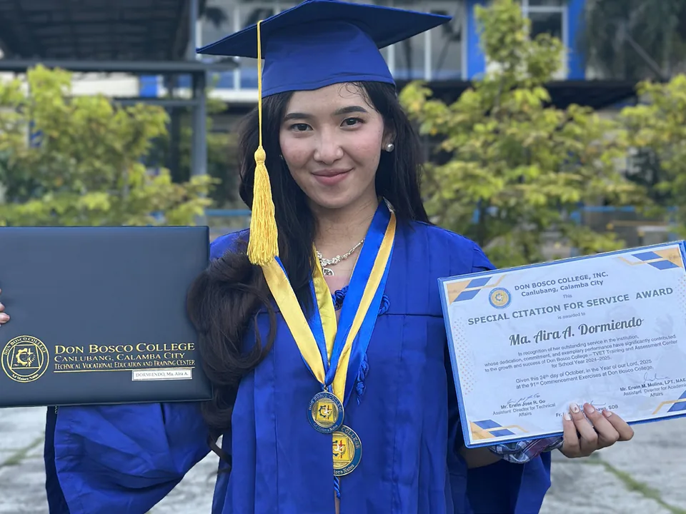 Ma. Aira Dormiendo holding her diploma and special citations after graduating as class valedictorian.