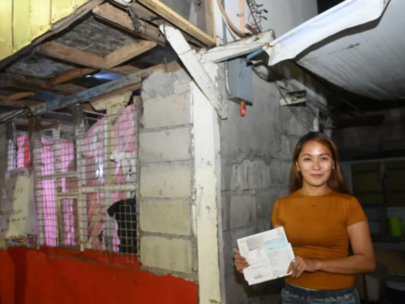 A woman holds her Meralco bills outside her home in Quezon City.