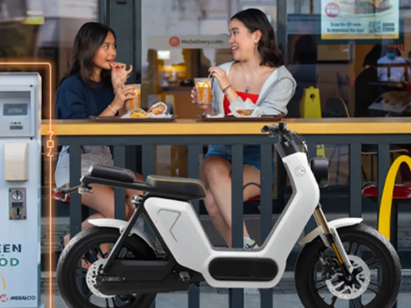 McDonald’s customers beside an electric scooter and Meralco-powered charging station.