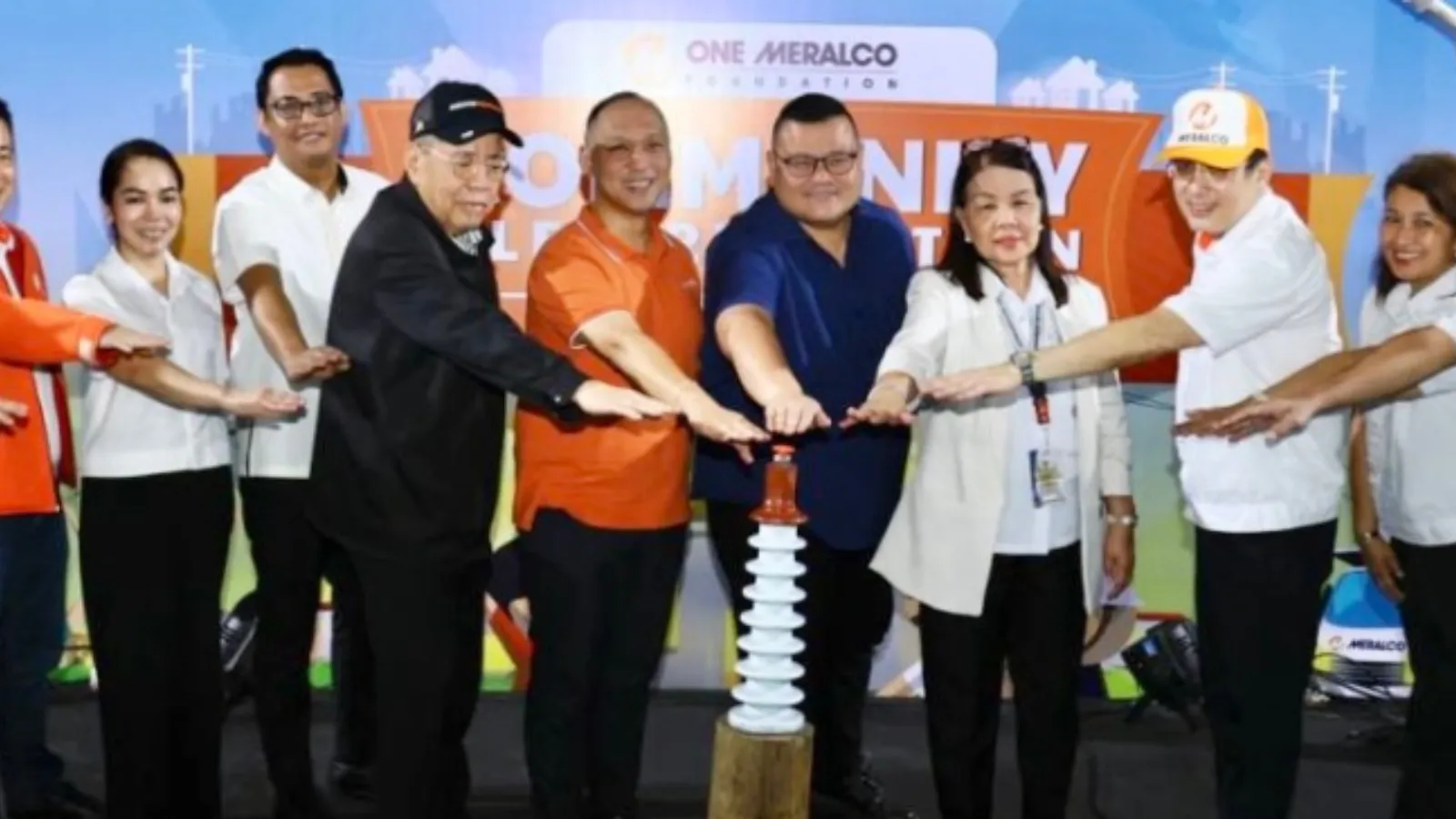 Participants place their hands over an electrical insulator during a One Meralco Foundation community electrification event.