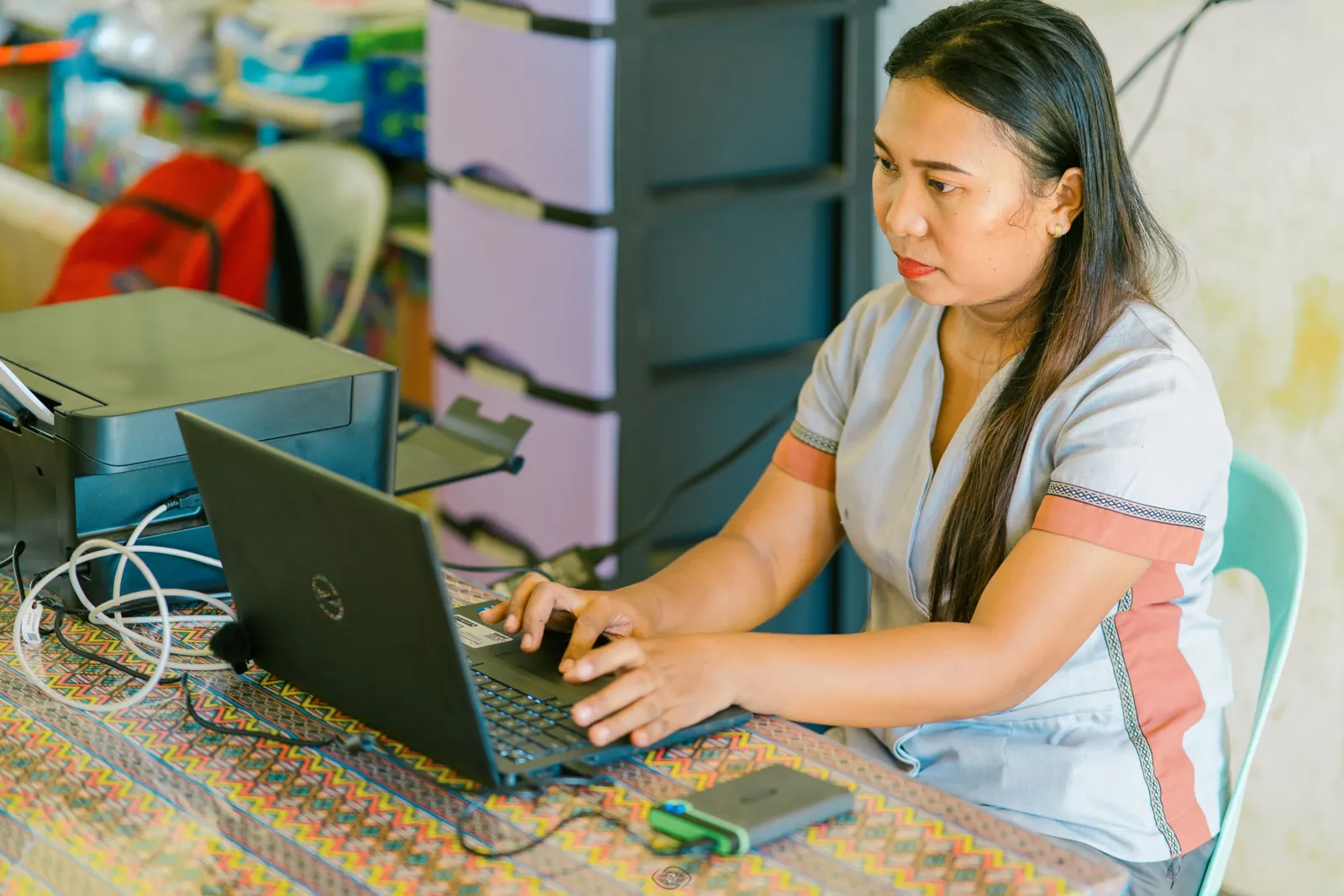 Analyn Miñao works on a laptop beside a printer in her classroom.