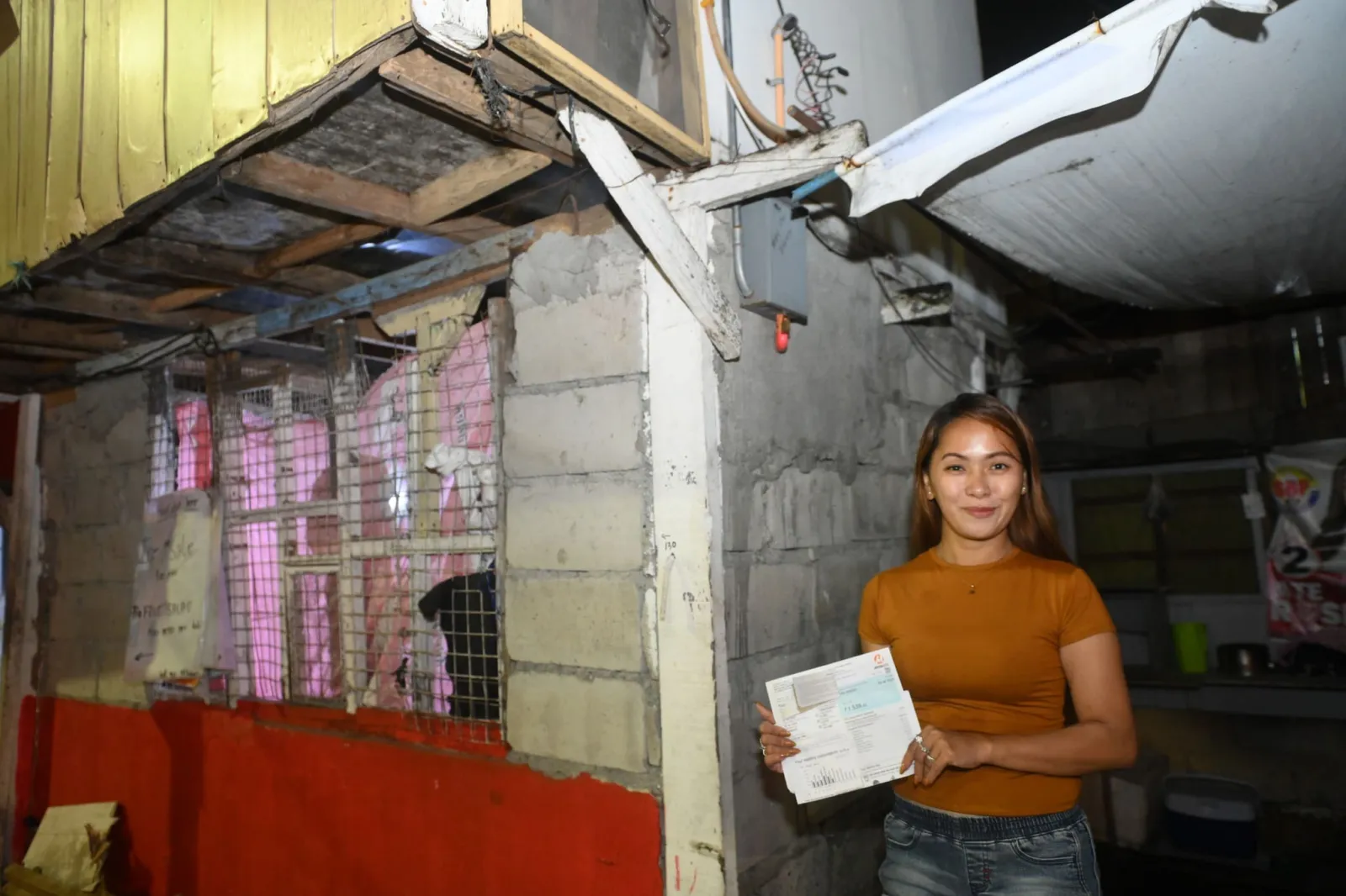 Maan Cruz-Atienza holds Meralco bills inside her home in Novaliches, Quezon City.