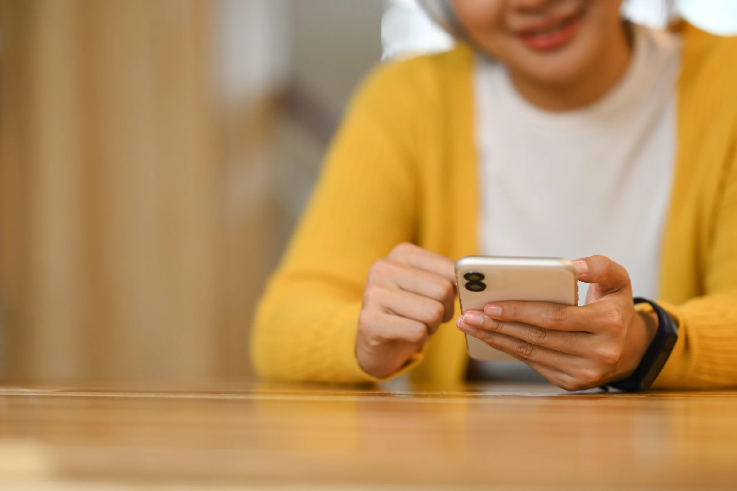 A person uses a smartphone at a table.