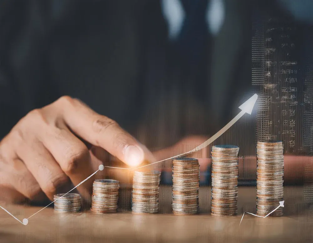 A hand places a coin on growing stacks of Philippine currency.