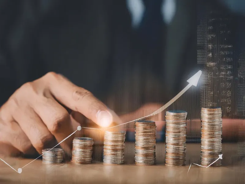 A hand places a coin on growing stacks of Philippine currency.