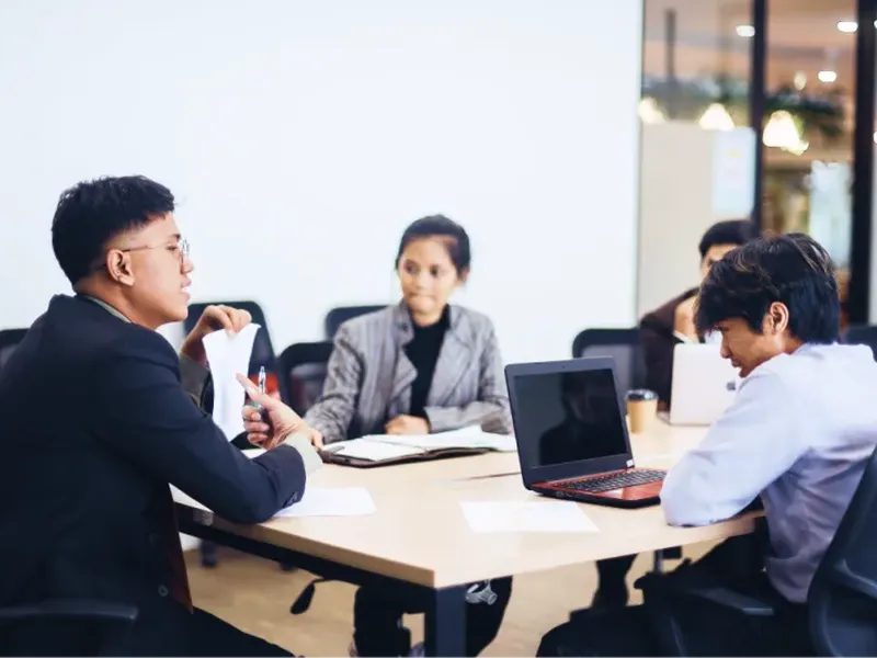 Investment analysts meet around a conference table.