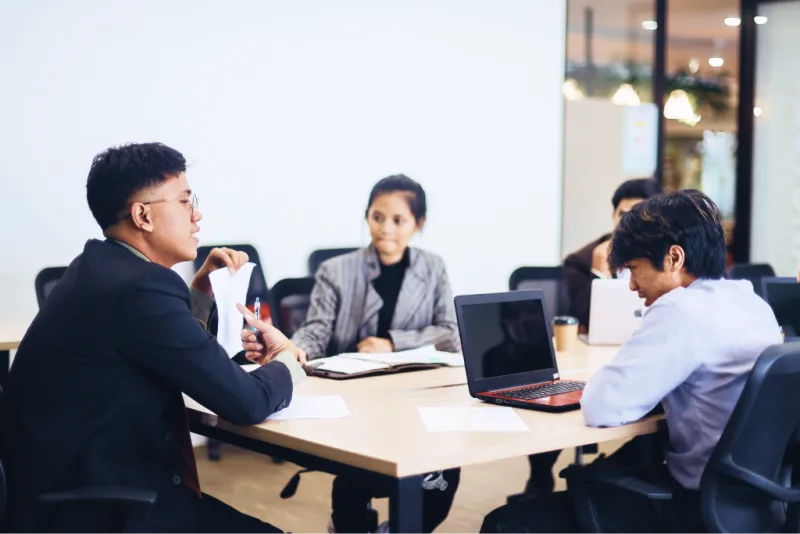 Investment analysts meet around a conference table.